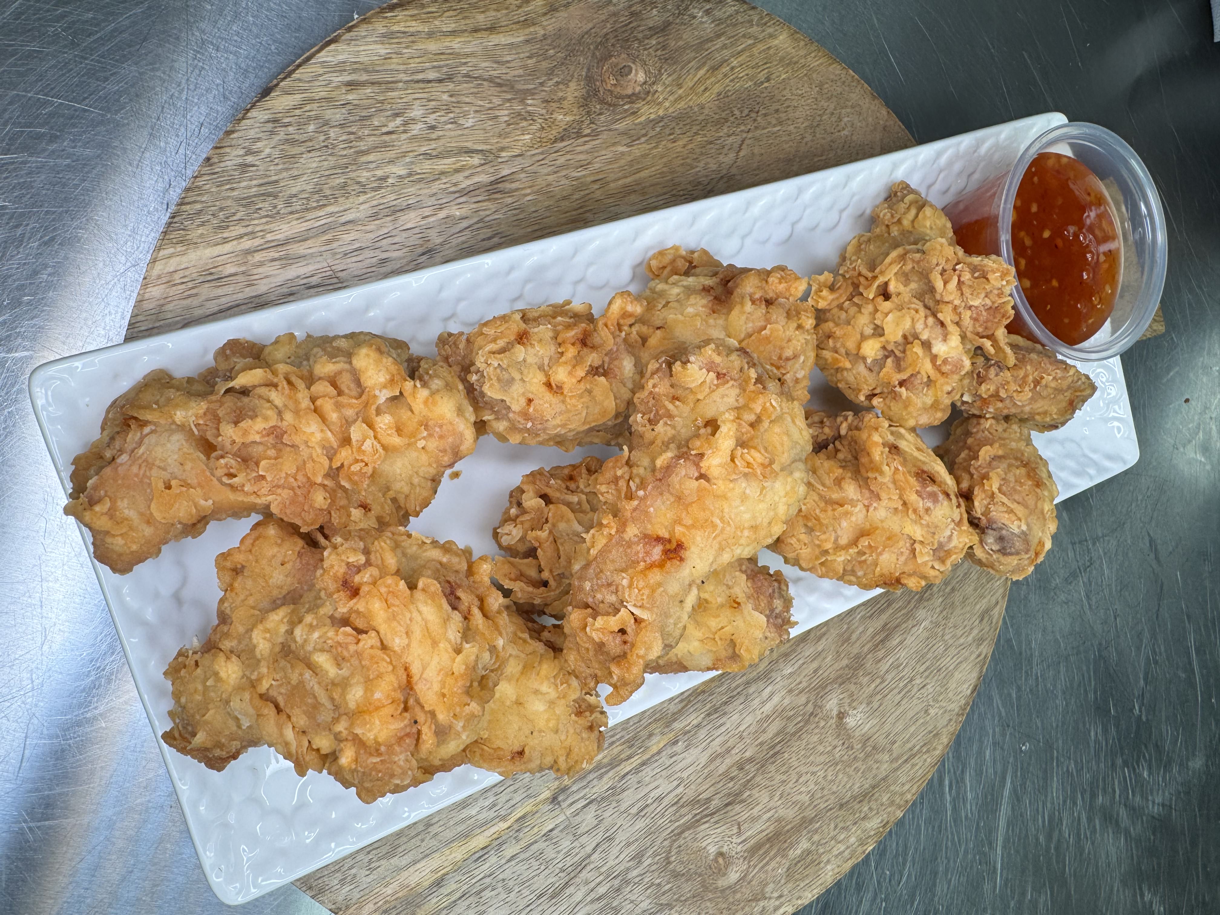 Plate of crispy chicken wings with a cup of dipping sauce from Jomaa's Capilano